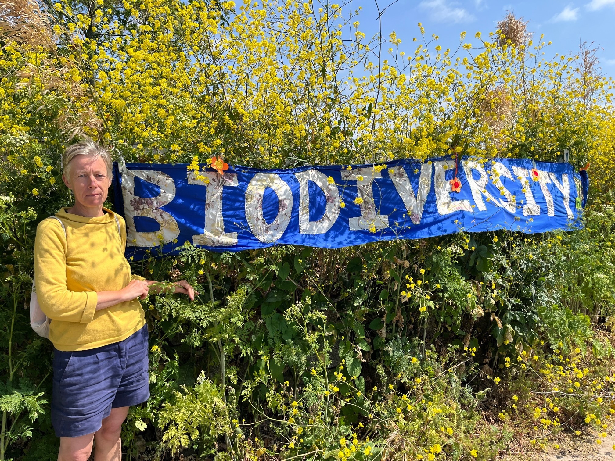 Sara Clasper, from Portreath Climate Action Network, with their banner near the land mooted for housing. (Pic: Lee Trewhela / LDRS)